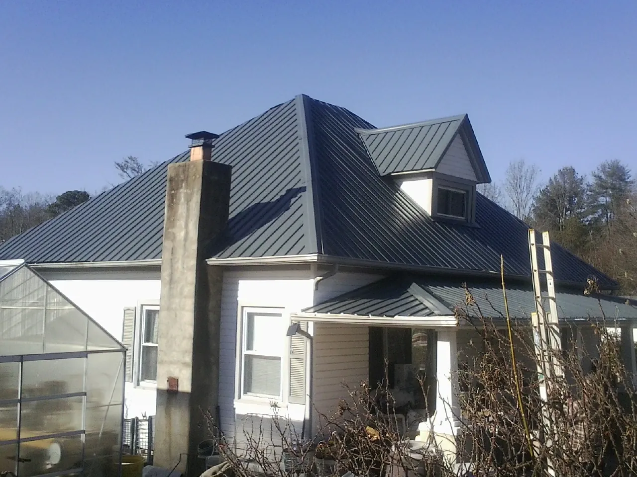 Dark blue standing seam metal roof on a white farmhouse with dormer — Slate & Tile Roof Repair by Roofing Brothers in Fleischmanns