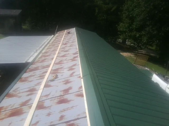 Old rusted panels beside newly installed green metal roofing — Wind Damage Roof Repair by Roofing Brothers in Fleischmanns