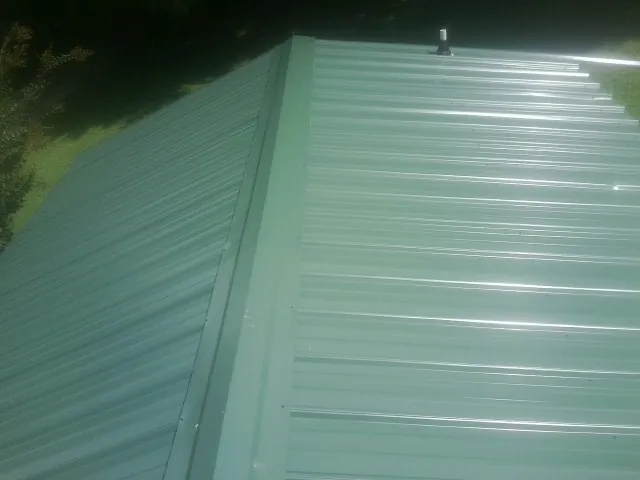 New green metal panels meeting at the ridge of a roof — Flat Roof Repair work by our crew in Fleischmanns