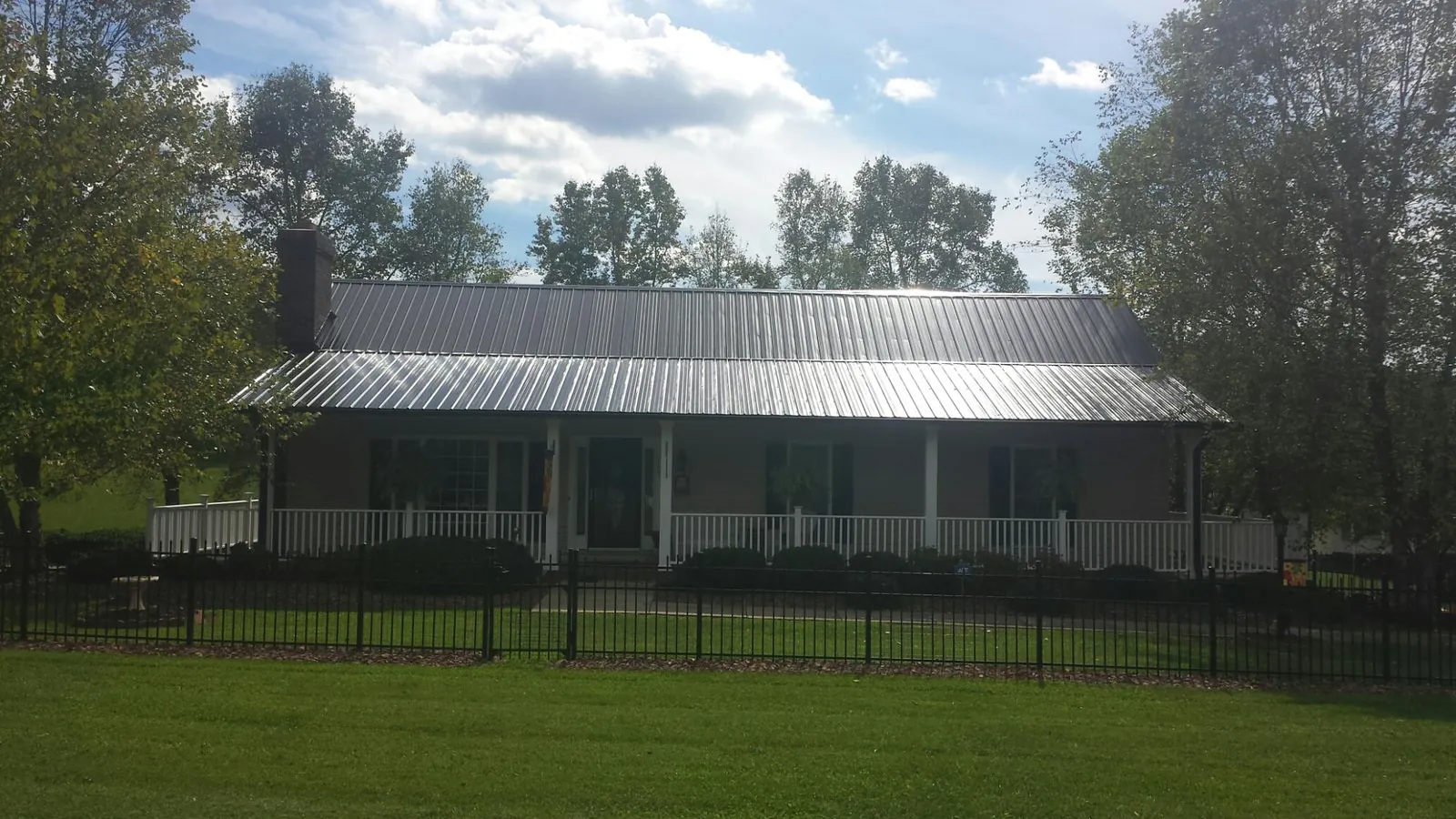 Gray metal roof on a brick ranch with a full width front porch — Gutter Guard Installation work by our crew in Fleischmanns