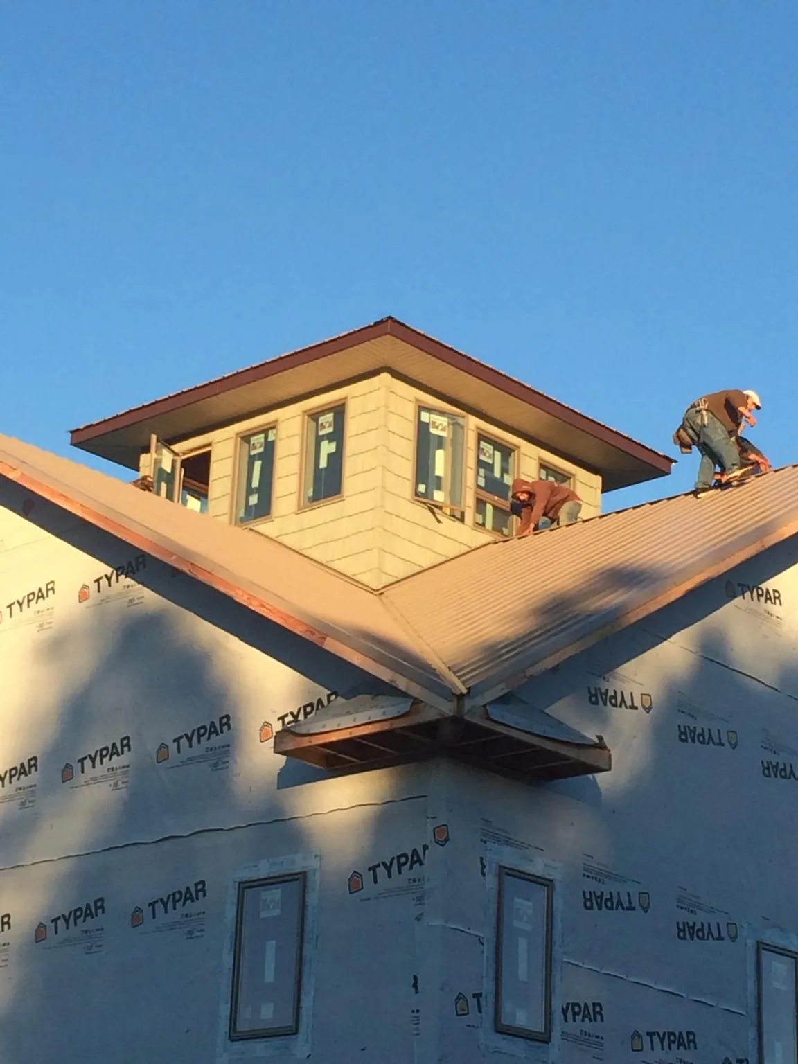 Roofers working around a rooftop cupola on a new metal roof at sunset — Roof Waterproofing in Fleischmanns by Roofing Brothers